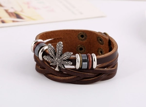 Gros plan du bracelet en cuir multicouche vintage avec breloque feuille et clous métal