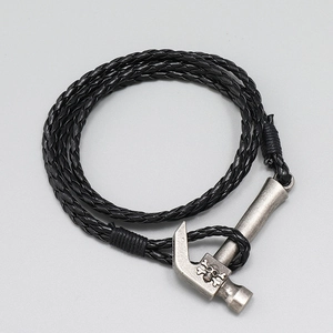 Close-up of woven leather multi-layer bracelet with vintage silver hammer and skull charm