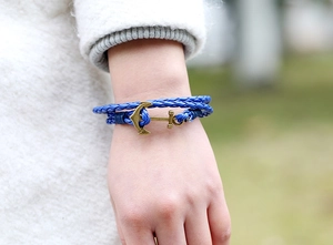 Close-up of deep blue braided leather bracelet with bronze anchor clasp worn on wrist