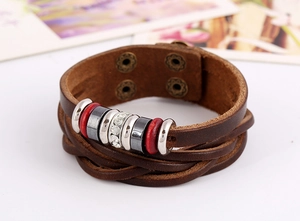 Detail of brown braided leather bracelet featuring rhinestone accents and metal snap buttons