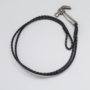 Macro shot of silver hammer pendant with skull relief on black braided leather strap
