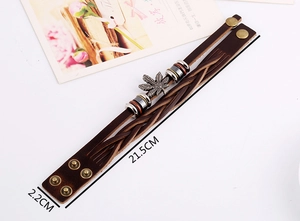 Détail du bracelet multicouche en cuir marron avec feuille d'érable et boutons-pression