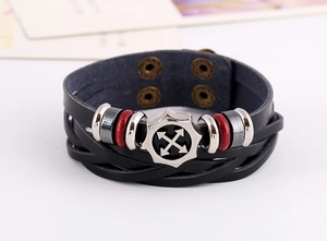 Detail of multi-layer leather bracelet with silver gear charm and cross arrow logo