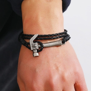 Close-up of men's leather wrap bracelet featuring a detailed skull hammer metal charm