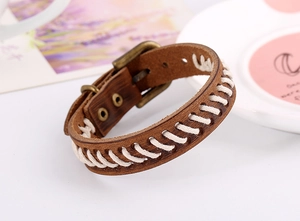 Détail du bracelet en cuir marron vintage avec couture tissée blanche et boucle bronze