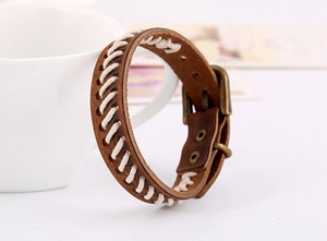 Gros plan d'un bracelet en cuir marron tressé avec surpiqûres blanches et boucle en laiton