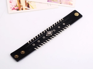 Détail du large bracelet punk en cuir noir avec bords tressés et boutons en métal