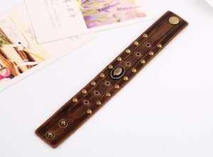 Détail du bracelet punk en cuir marron foncé avec rivets dorés vintage et boucle métal