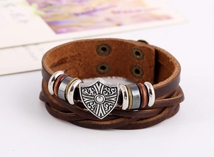 Macro shot of multi-layer woven brown leather bracelet with vintage silver shield charm