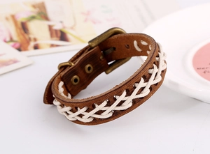 Detail des braunen geflochtenen Lederarmbands mit weißer Naht und bronzener Metallschnalle