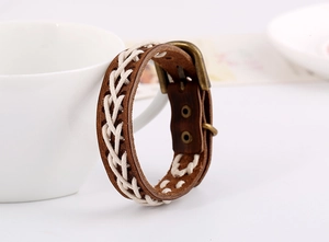 Nahaufnahme eines gewebten braunen Lederarmbands mit weißer Baumwollkordel und Bronzeschnalle