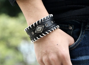 Gros plan du bracelet large en cuir punk avec coutures blanches croisées et détail métal