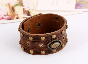 Détail d'un bracelet punk en cuir marron avec des rivets en bronze et ornement relief