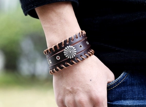 Details eines dunkelbraunen Lederarmbandes mit silberner Sonnenblume und gewebtem Rand
