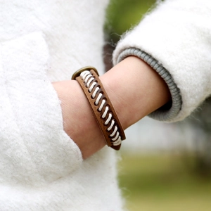 Bracelet en cuir marron vintage avec coutures blanches et fermoir bronze au poignet