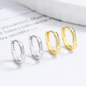 Macro shot of oval silver and gold hoop earrings with cubic zirconia inlay and dotted texture