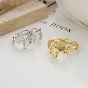 Macro view of gold and silver ginkgo leaf rings with brushed texture and zircon accents