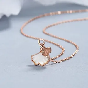 Macro shot of rose gold ginkgo leaf necklace with delicate white shell and fine textures