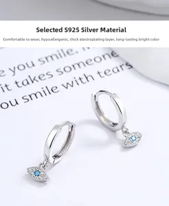 Macro detail of S925 sterling silver evil eye earrings with blue gem and crystals