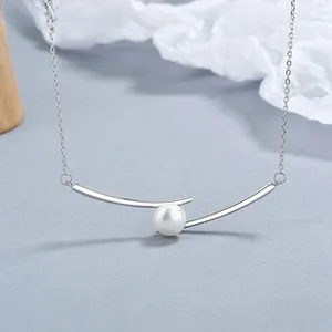Macro detail of 925 sterling silver curved bar necklace with a round white pearl charm