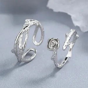 Detailed macro view of 925 sterling silver rose flower and vine rings on gray surface