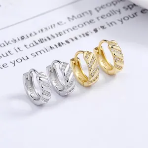 Macro shot of 925 sterling silver twist hoop earrings with pavé crystals in gold and silver