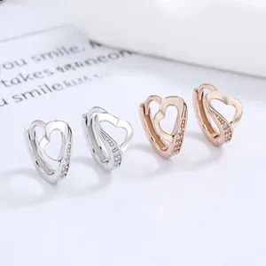 Detail of silver and rose gold heart hoop earrings with side-set cubic zirconia stones