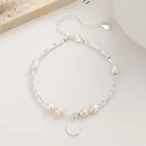 Detailed macro shot of 925 silver pearl bracelet with heart charm and delicate link chain