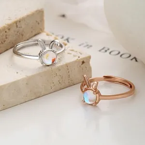Macro detail of silver and rose gold rabbit rings with moonstone on stone background