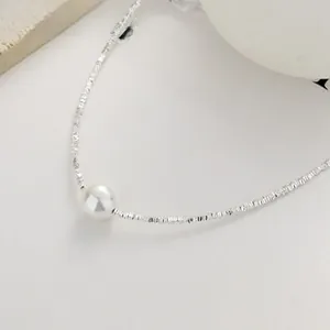 Macro detail of 925 silver faceted chain necklace with a round white pearl pendant