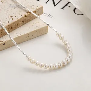 Detailed view of 925 sterling silver butterfly necklace with pearls on a stone slab