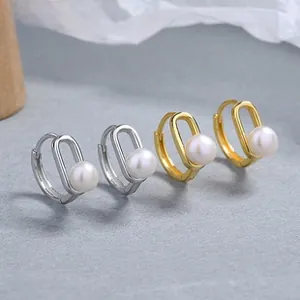 Detail of geometric silver pearl earrings in gold and silver finishes with hollow design