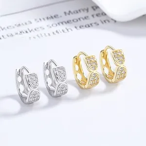 Close-up of gold and silver geometric hoop earrings with pavé cubic zirconia inlay