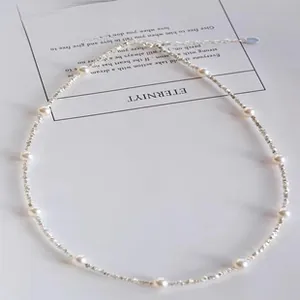 Close-up of 925 silver beaded pearl necklace with heart pendant on white paper