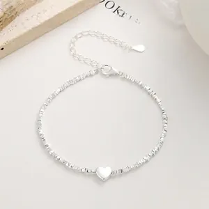 Macro shot of 925 sterling silver beaded bracelet with heart charm on stone surface