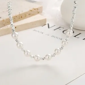 Close-up of 925 silver bow necklace with white pearls and silver beads on a stone tray