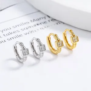Close-up of gold and silver square charm hoop earrings with sparkling zircon crystals