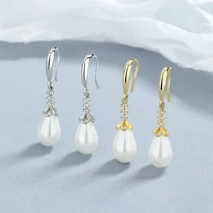 Detail of silver and gold pearl drop earrings with zircon floral caps and ear hooks