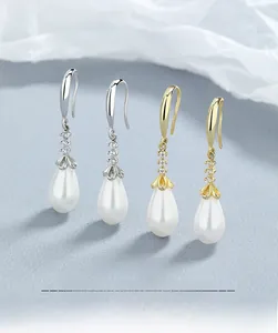 Detail view of silver and gold pearl earrings with small diamonds and teardrop pearls