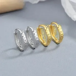 Macro detail of 925 sterling silver hoop earrings with geometric diamond-cut pattern