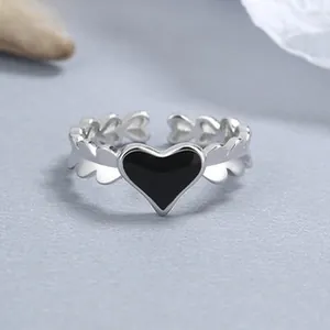 Detail of 925 silver open ring featuring a black enamel heart and angel wing motifs