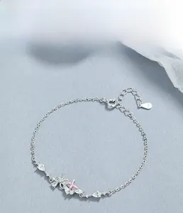 Gros plan du poinçon S925 et du charm fleur en émail rose sur le bracelet en argent