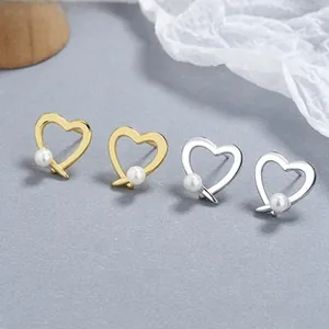 Close-up of gold and silver heart-shaped 925 sterling silver earrings with small white pearls