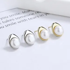 Macro shot of 925 silver and gold pearl stud earrings with polished metallic base
