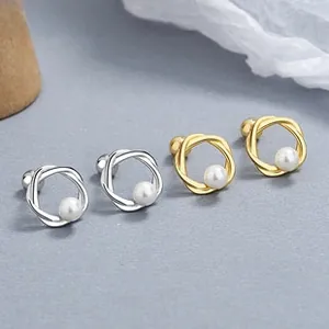 Detail of twisted spiral gold and silver stud earrings with center white pearl inlay