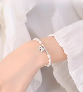 Detailed view of the freshwater pearl bracelet with a silver bow pendant on model wrist