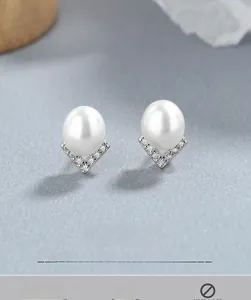 Macro detail of 925 silver pearl earrings with a V-shaped pavé-set zircon base
