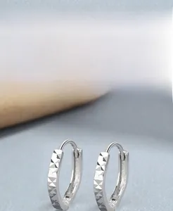 Macro shot of geometric faceted S925 sterling silver hoop earrings with high-shine finish