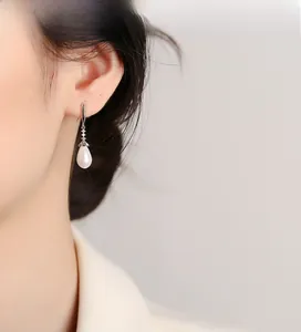 Close-up of teardrop pearl earrings with silver hooks and sparkling zircon accents