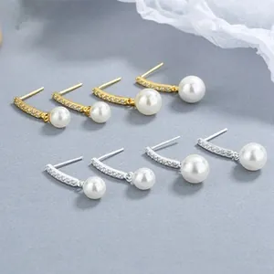Detail of silver and gold pearl stud earrings with crystal pave on a textured surface
